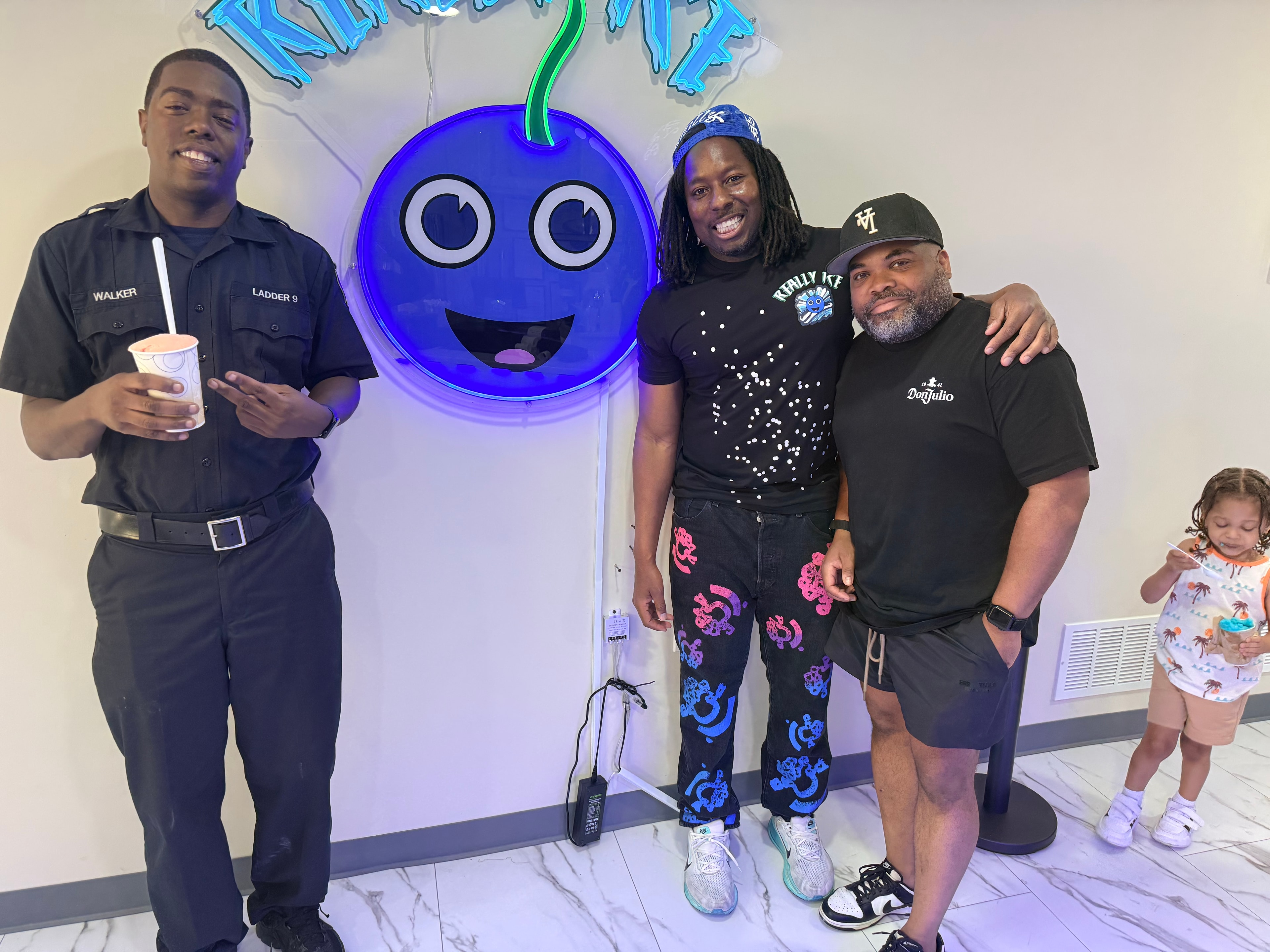Dean Owens with a Philadelphia firefighter from Ladder 9 and a guest in front of the Really Ice mascot logo