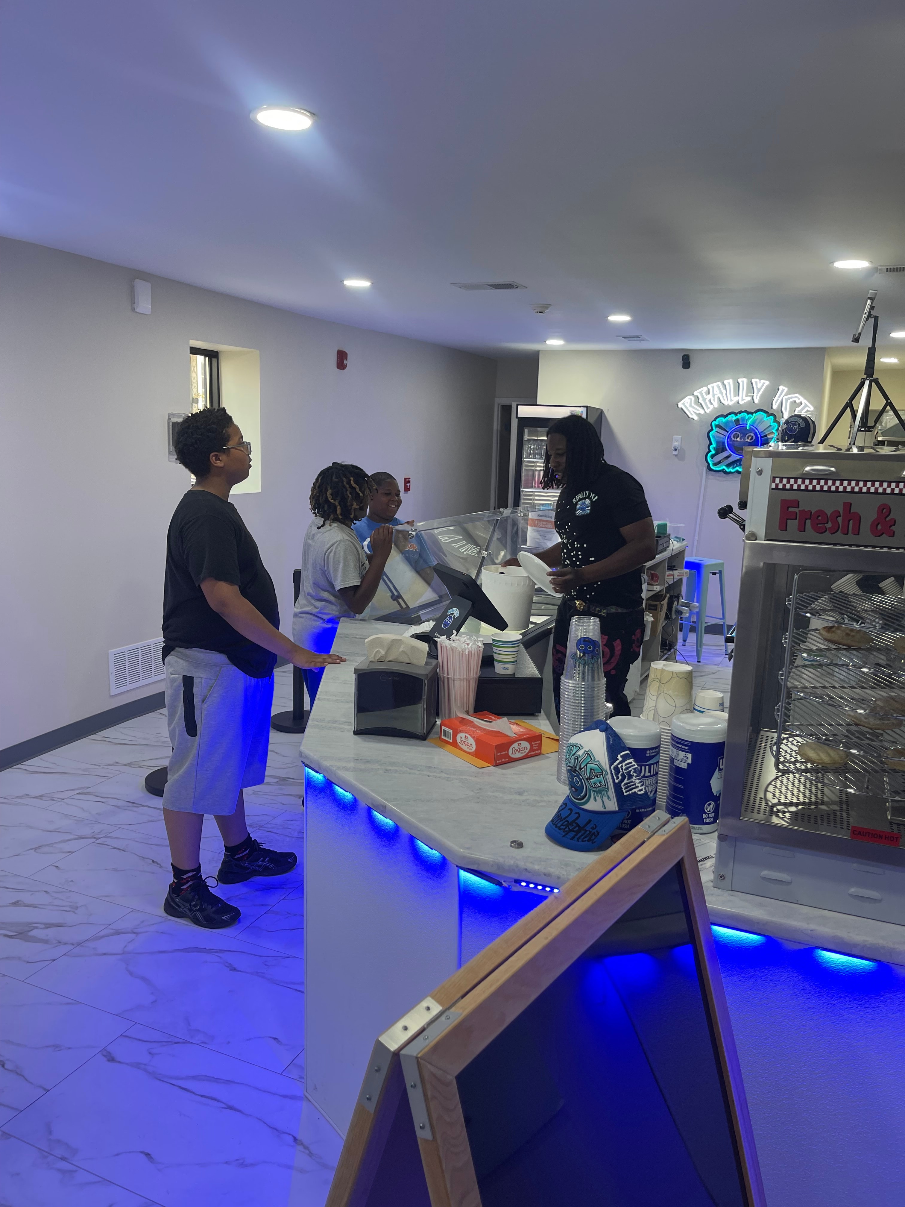 Really Ice staff serving customers at the counter with blue LED lighting and the Really Ice neon sign