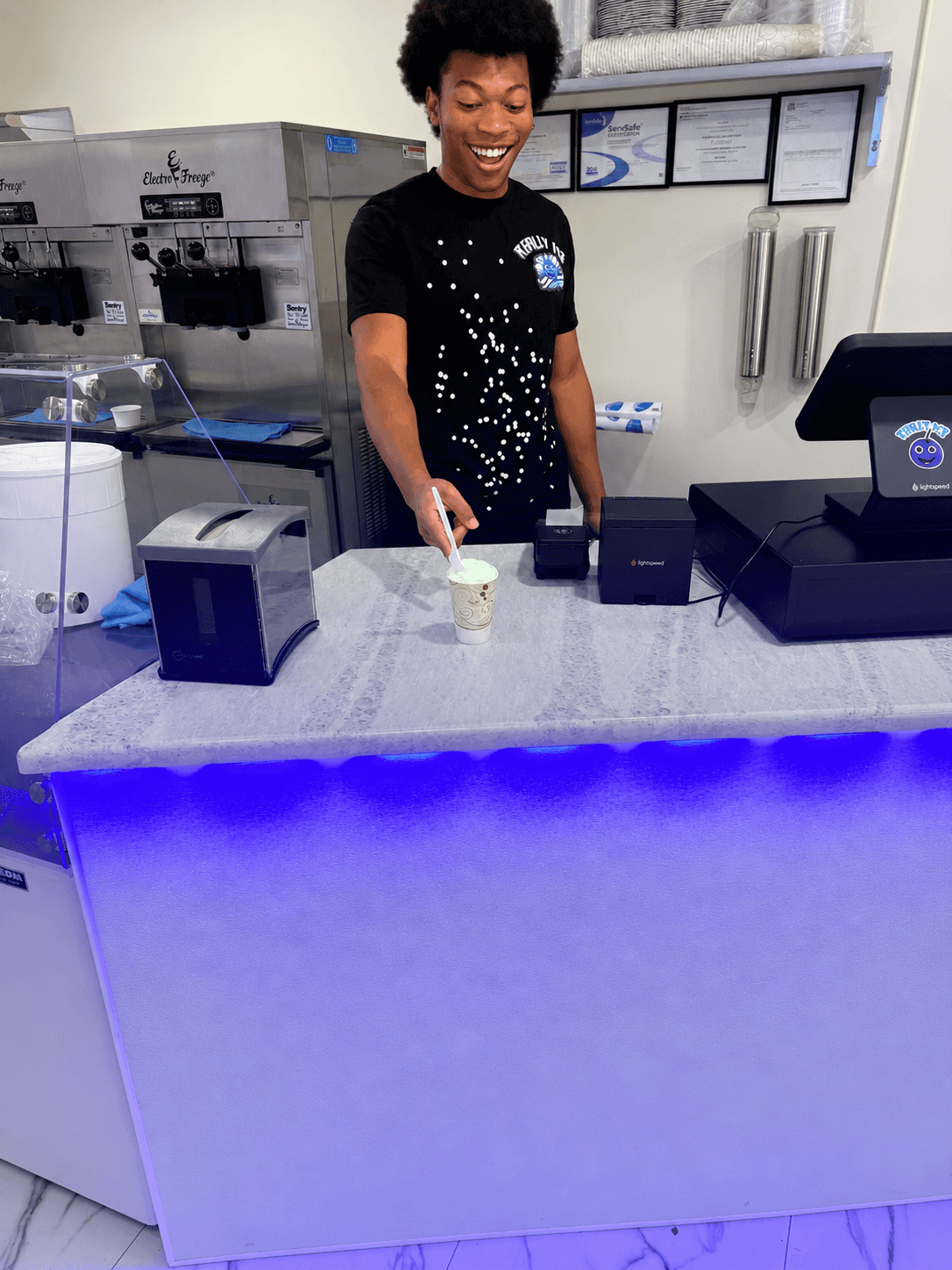 A Really Ice team member smiling while serving a cup at the counter